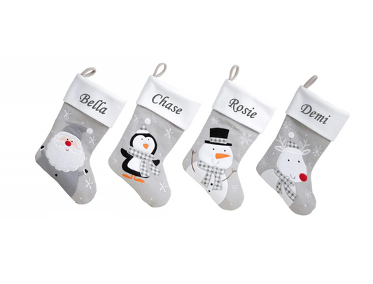 Four Christmas stockings with snowman, penguin, and reindeer designs on a white background.